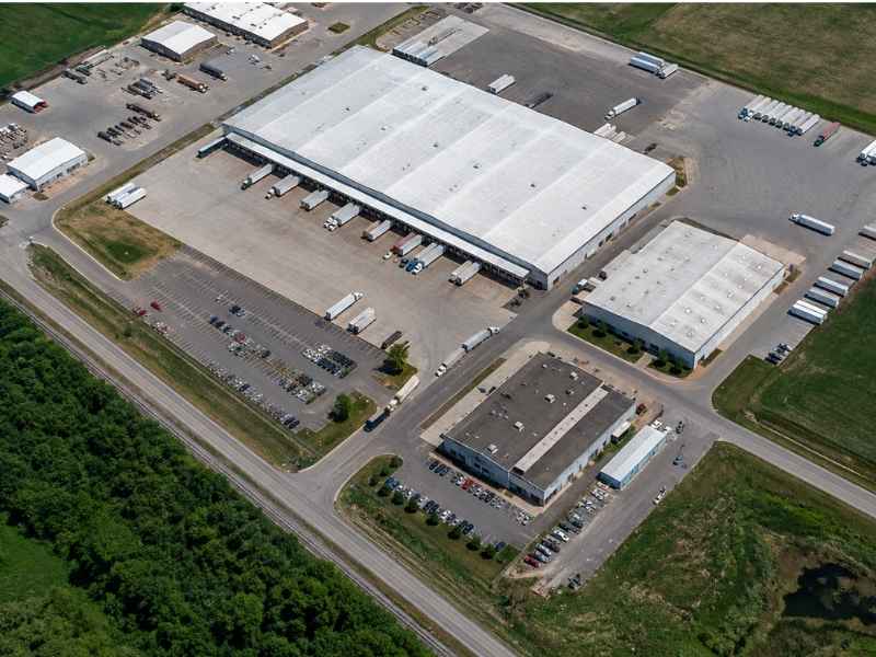 Aerial survey data industrial site planning munford alabama - Maxwell Land Surveying Aerial view of a large warehouse complex with loading docks, parking lots, and adjacent office buildings.